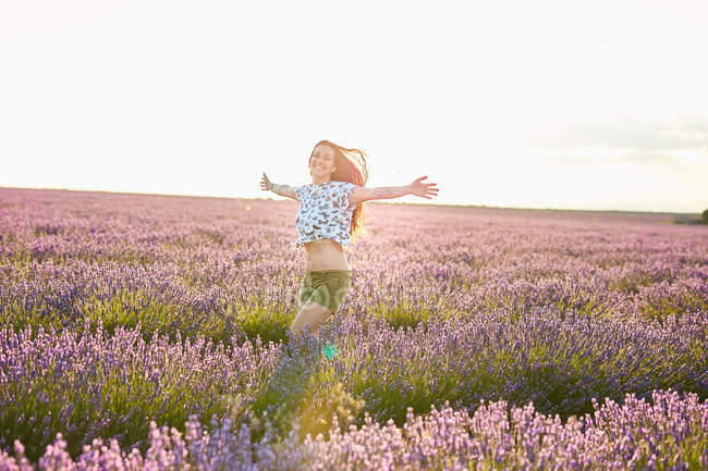 Giovane donna che corre tra il campo di lavanda viola — Foto stock
