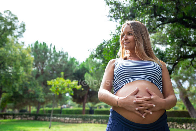 Pregnant girl crossing her hands in the gut — Stock Photo