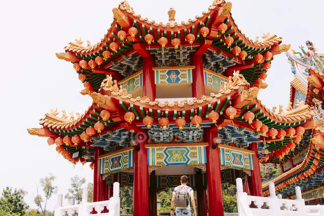 Back view young guy with backpack going up in colourful wonderful Asian building in Malaysia — Stock Photo