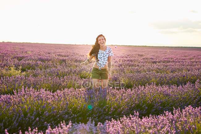 Jeune femme debout entre champ de lavande violette — Photo de stock