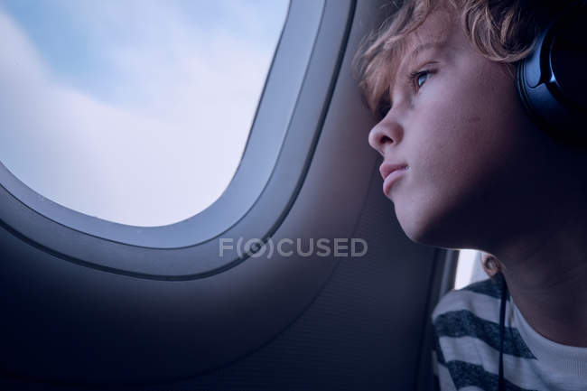Netter Junge mit Kopfhörern im Flugzeug — Stockfoto