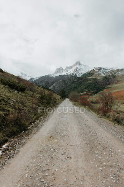 Ruta de campo en valle con bosques y montañas maravillosas en la nieve en los Pirineos - foto de stock