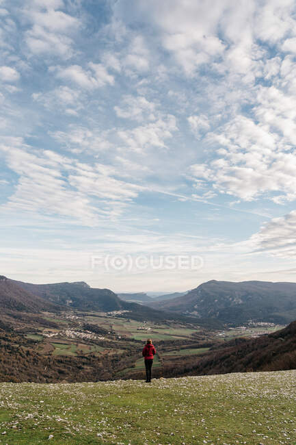 Back view of female traveler looking at majestic valley and spectacular mountain ridge on cloudy day in Navarre, Spain — Stock Photo