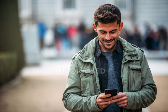 Jeune homme sur le téléphone portable et marchant à madrid pendant l'hiver — Photo de stock