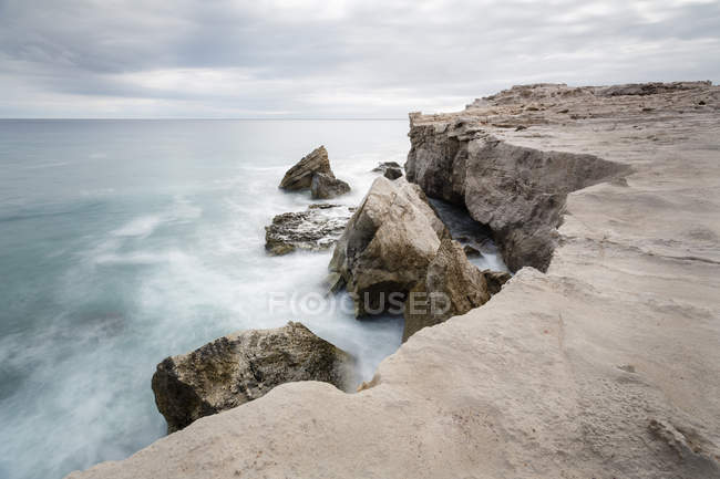 Груба кам'яна скеля і хвилясте штормове море під хмарним небом — стокове фото