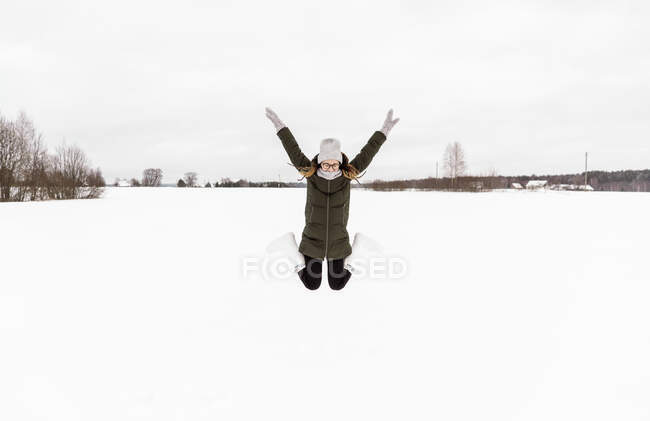 Woman jumping between snow field — Stock Photo