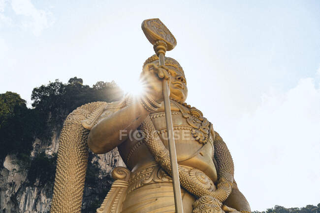 From below Asian monument near stone cliff and blue sky in Malaysia — Stock Photo