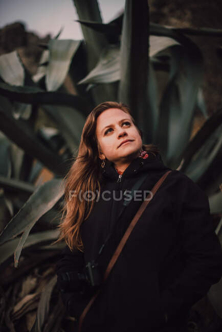 Mujer de abrigo con cámara cerca de plantas - foto de stock