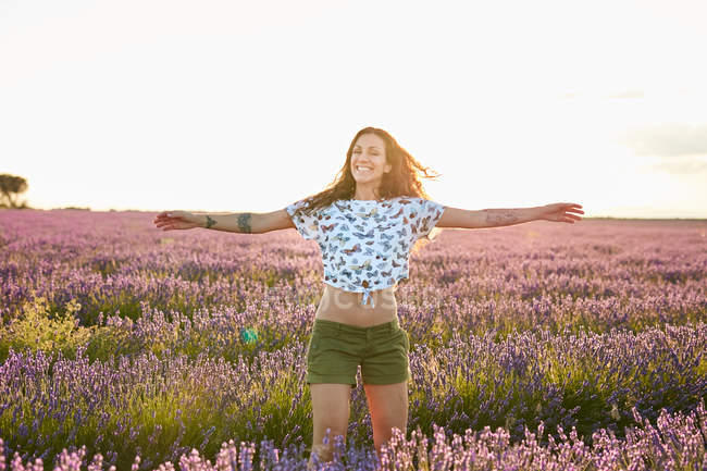 Sorrindo jovem mulher girando no campo de lavanda violeta grande — Fotografia de Stock