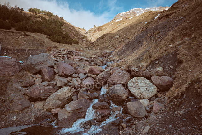 Pequeno riacho em colina pedregosa em montanhas — Fotografia de Stock