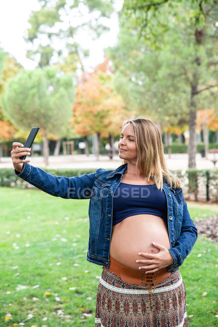 Mulher atraente grávida usando telefone celular — Fotografia de Stock