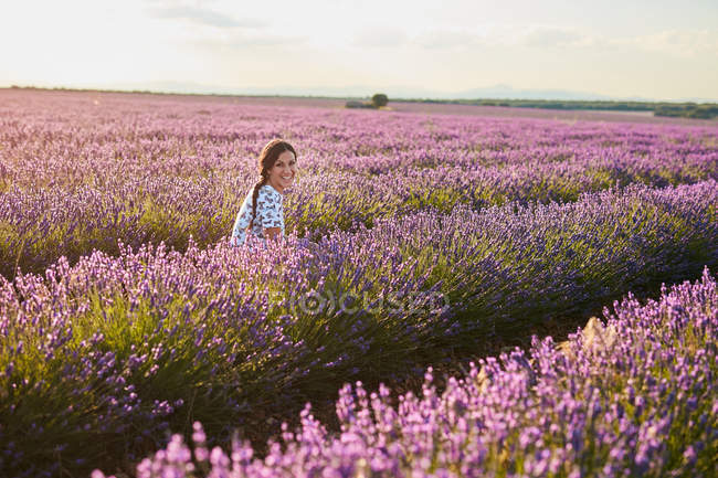 Молода жінка сидить між фіолетовим лавандовим полем — стокове фото