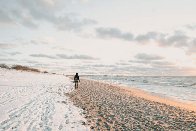 Woman walking on snow coast near sea — Stock Photo
