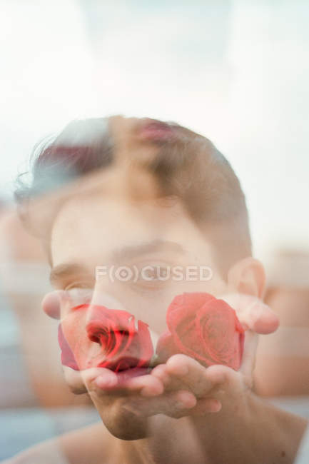 Morena joven sin camisa chico mostrando rosas frescas vinosas y mirando a la cámara en un fondo borroso - foto de stock