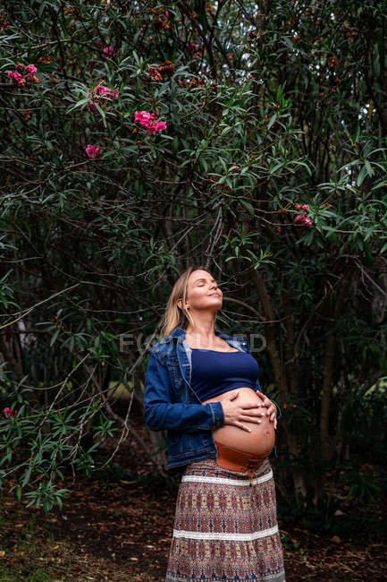 Улыбающаяся беременная привлекательная женщина в парке — стоковое фото