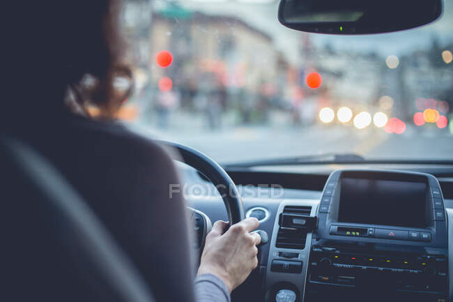 Back view crop lady driving automobile on street in evening in San Francisco, USA — Stock Photo