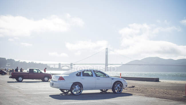 Гарний легкий автомобіль на парковці біля узбережжя океану і чудовий міст у сонячній погоді у Сан - Франко (уса). — стокове фото