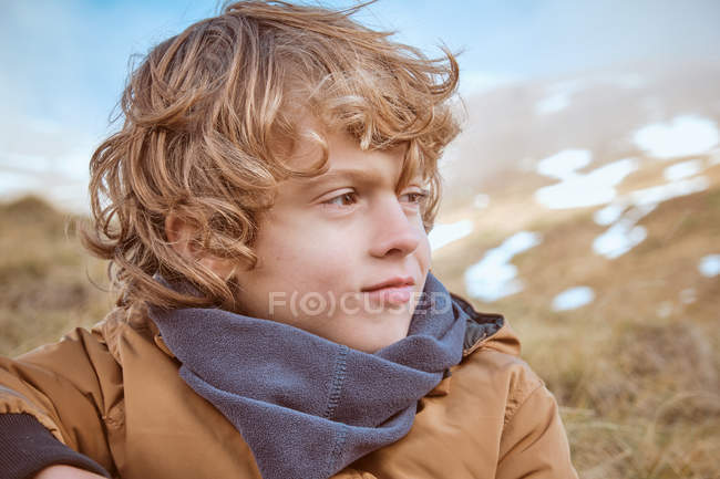 Carino ragazzo seduto sulla collina vicino al ruscello — Foto stock