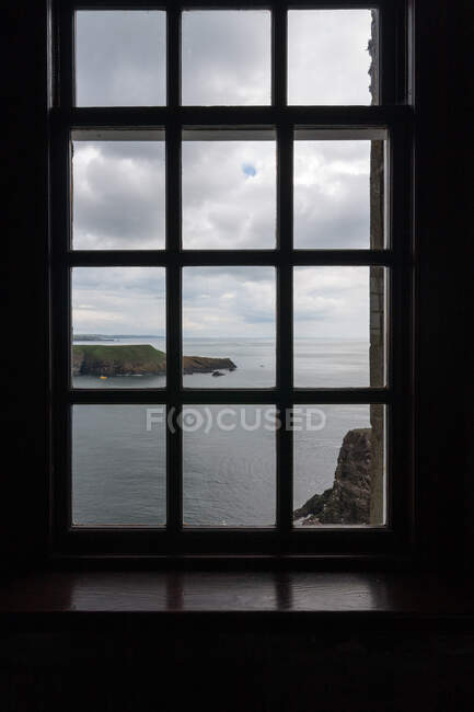Величественный вид на красивое море и скалы из окна дома в пасмурный день — стоковое фото