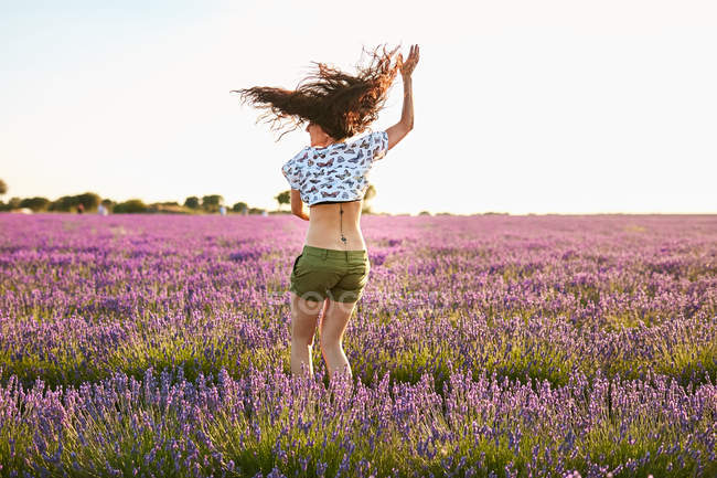Jeune femme tourbillonnant entre champ de lavande violette — Photo de stock