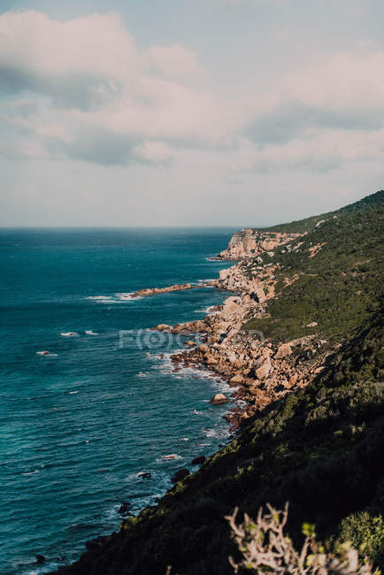 Costa rocosa y aguas azules tranquilas - foto de stock
