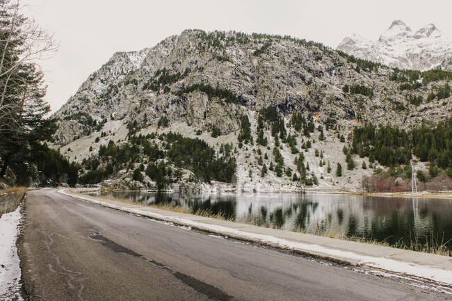 Snowy route running between mountains and a lake in Pyrenees — Stock Photo