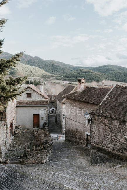 Vue panoramique de l'ancienne ville près de hautes collines avec forêt et ciel bleu avec nuages dans les Pyrénées — Photo de stock