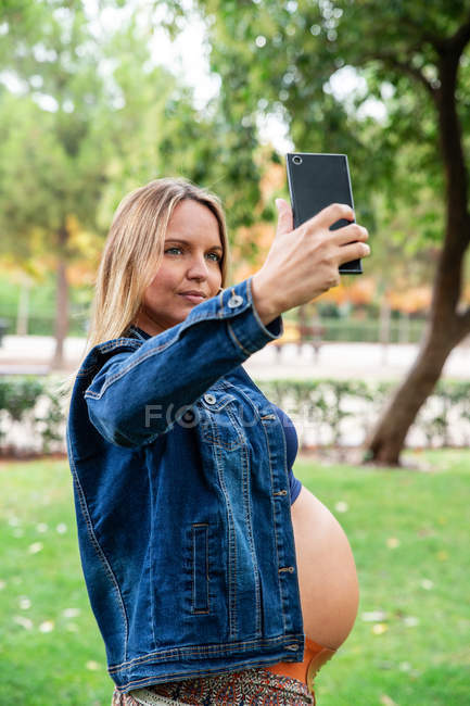 Mujer atractiva embarazada usando teléfono móvil - foto de stock