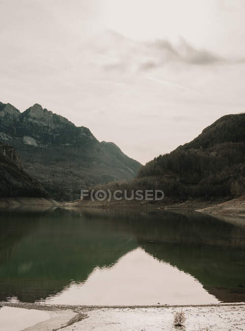 Amazing view of water surface between high mountains with trees on cloudy heaven in Pyrenees — Stock Photo