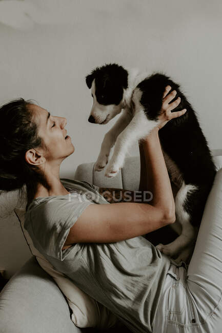 Adolescente chica con lindo cachorro en sofá - foto de stock