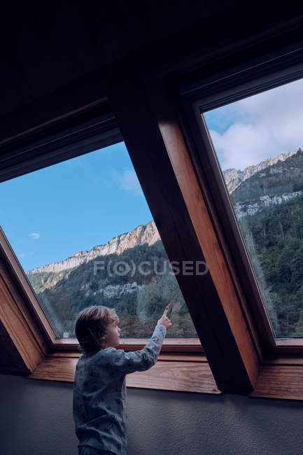 Boy looking at mountain through window — Stock Photo