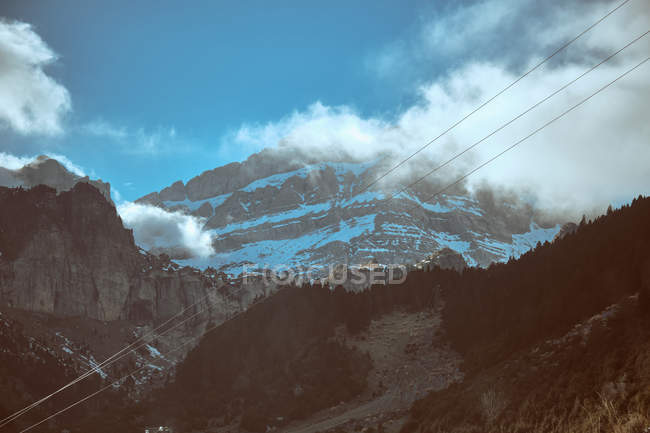 Nuvola su maestose montagne rocciose sotto il cielo blu — Foto stock