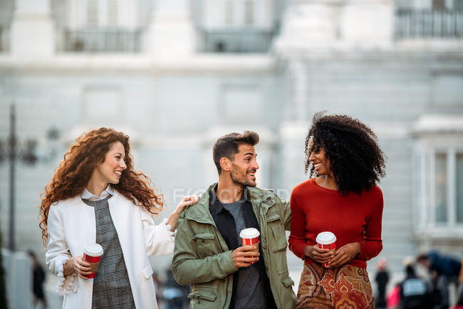 Trois jeunes amis marchant et buvant du café dans les rues de Madrid en hiver — Photo de stock