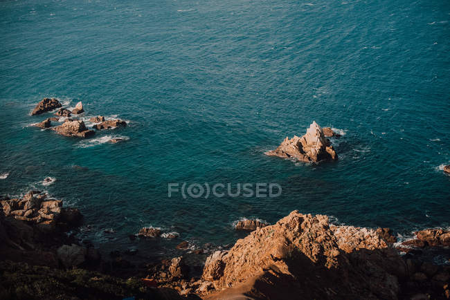 Côte rocheuse et eau de mer bleue calme — Photo de stock
