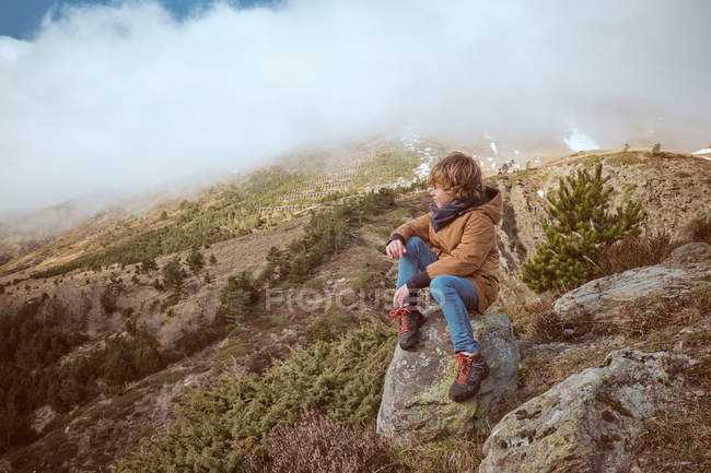 Junge sitzt an nebligem Tag in Hügelnähe — Stockfoto