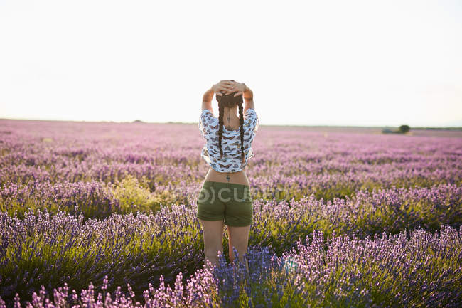 Junge Frau steht im violetten Lavendelfeld — Stockfoto
