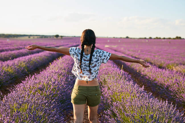 Junge Frau steht zwischen violettem Lavendelfeld — Stockfoto