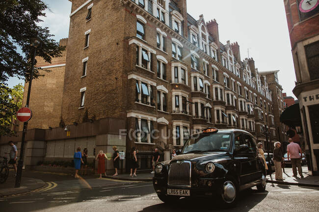 LONDON, UNITED KINGDOM - OCTOBER 23, 2018: Vintage автомобіль і натовп людей, що рухаються біля стародавніх будинків на красивій вулиці Лондона, Англія. — стокове фото