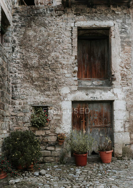 Hof mit Pflanztöpfen zwischen grauem Felsen altes Haus mit Holzfenstern in den Pyrenäen — Stockfoto