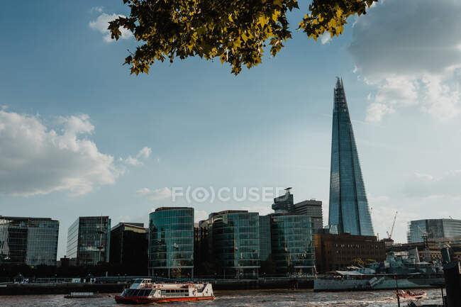 LONDRES, REINO UNIDO - 23 DE OCTUBRE DE 2018: Barco moderno flotando en el río Támesis cerca del distrito financiero de Londres, Inglaterra - foto de stock