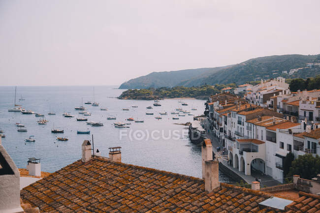 Varios pequeños buques flotando cerca de la increíble ciudad costera con casas maravillosas - foto de stock