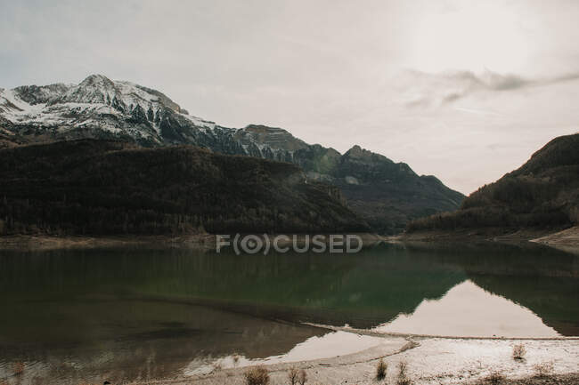 Amazing view of water surface between high mountains with trees on cloudy heaven in Pyrenees — Stock Photo