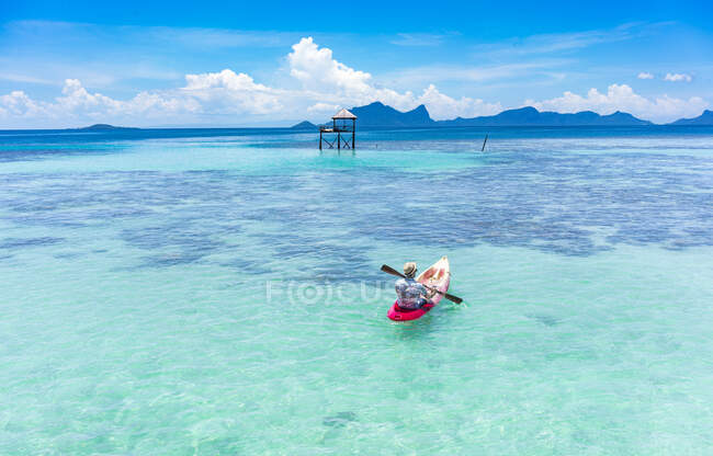 Back view male boating on canoe with paddle on amazing azure sea and blue sky in Malaysia — Stock Photo
