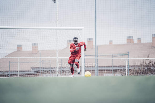 Афріканський футболіст з червоним нарядженням грає у футбол.. — стокове фото