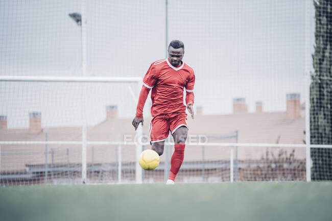Афріканський футболіст з червоним нарядженням грає у футбол.. — стокове фото