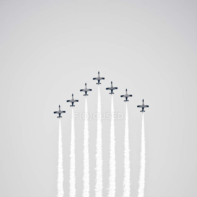 Gruppe von Jets, die farbigen Rauch ausstoßen, während sie vor klarem blauen Himmel fliegen — Stockfoto