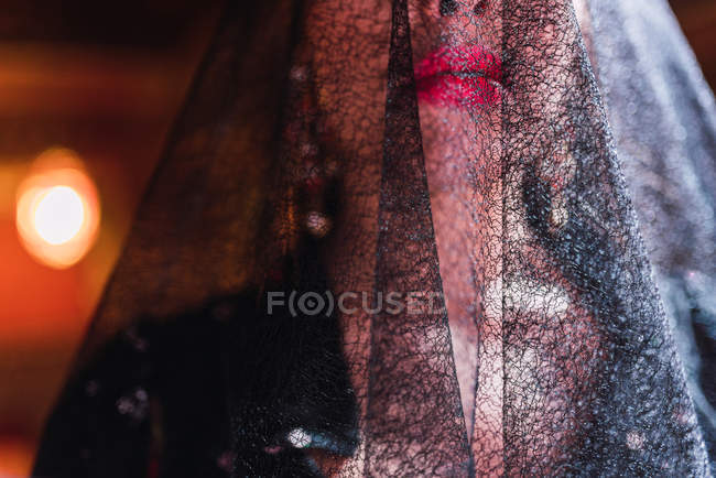 Cropped image of woman in veil and dress on scene illuminated by lights on blurred background — Stock Photo