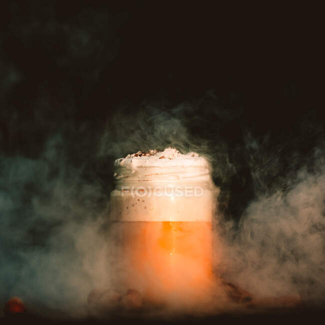 Une fine fumée blanche se répand sur la table avec un pot de café frais et des épices aromatiques — Photo de stock