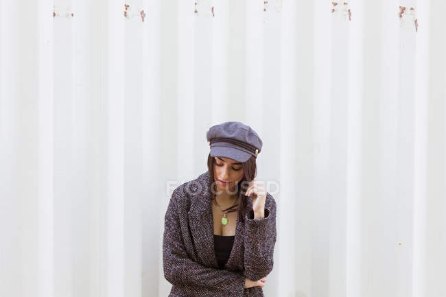 Стильна латиноамериканського дама в пальто і шапочка позують проти білої стіни — стокове фото