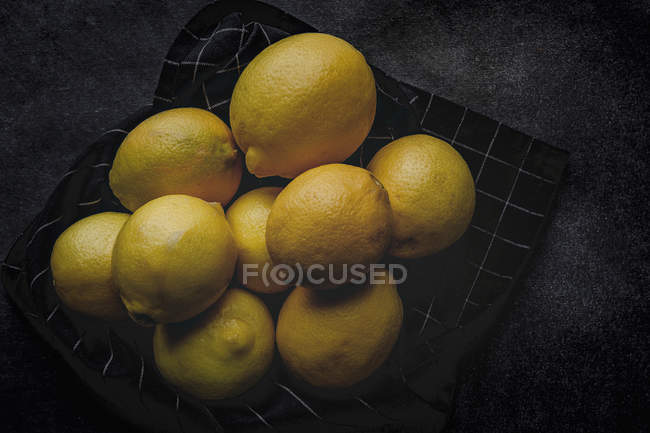 Haufen frischer Zitronen auf Serviette auf dunklem Hintergrund — Stockfoto